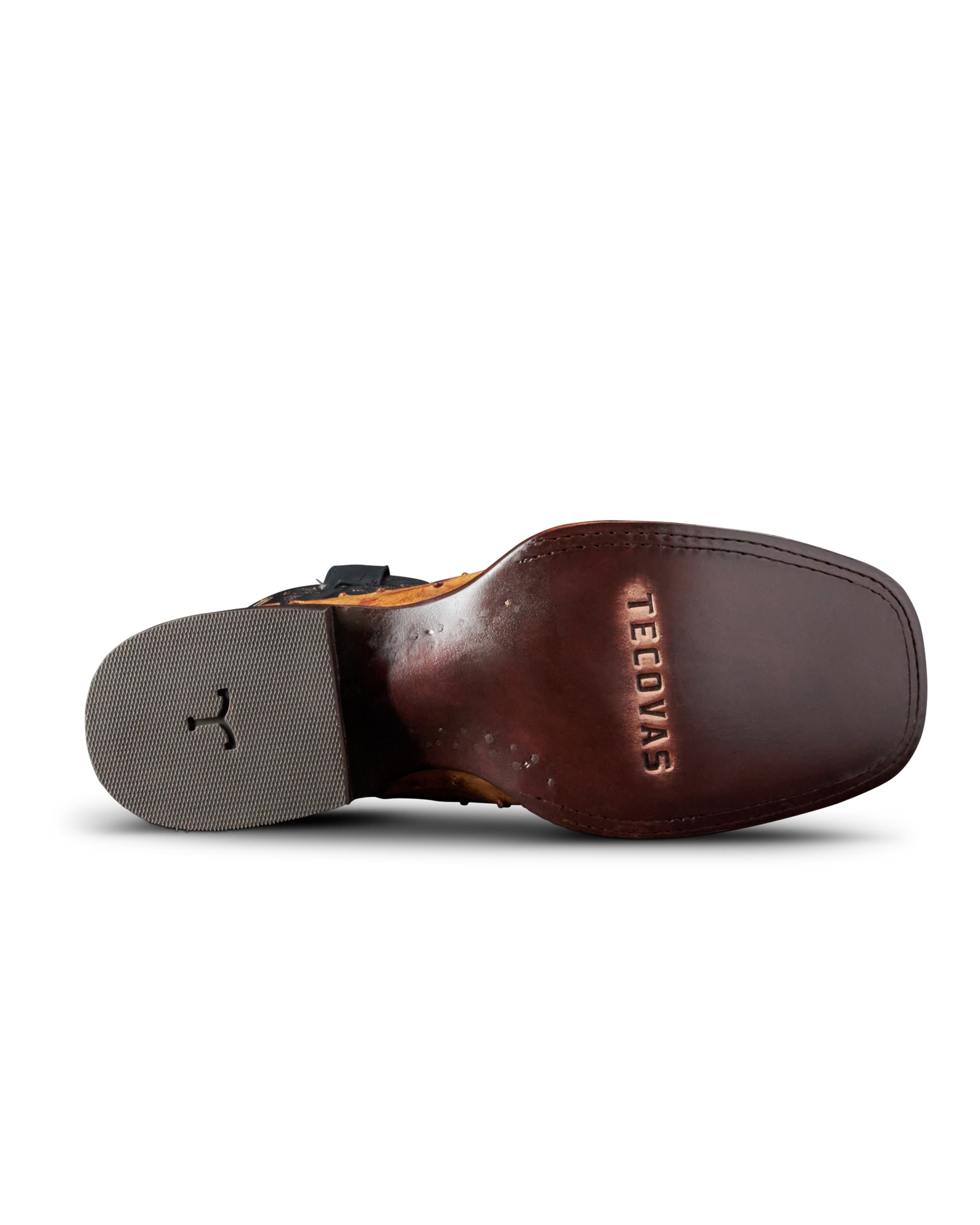 A close-up bottom view of a brown leather boot sole, showing the embossed brand name 'TEEDYAS' on the heel bed and a gray outsole with a black logo.