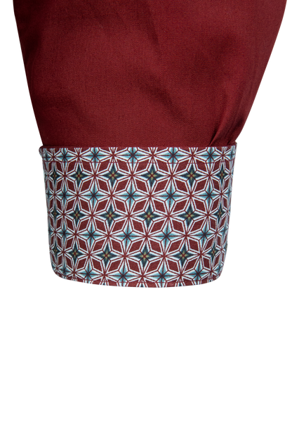Close-up of a shirt cuff showing a solid burgundy upper section and a patterned lower cuff with a geometric star motif in burgundy, teal, and white.